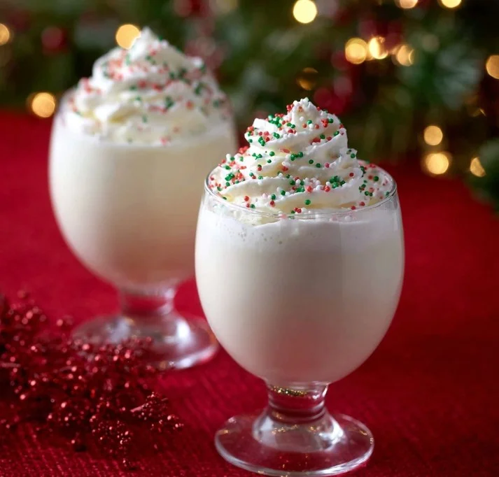Creamy White Christmas Punch in a festive glass garnished with mint.