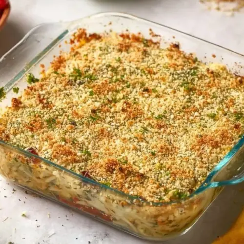 White bean and pesto bake topped with cheese and herbs in a baking dish