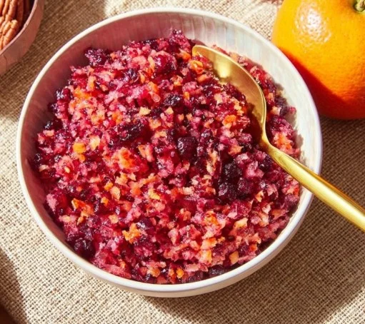 Homemade cranberry orange relish served in a bowl with fresh oranges and cranberries