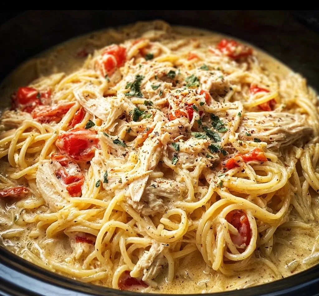 Creamy crockpot chicken spaghetti served in a bowl with herbs on top.