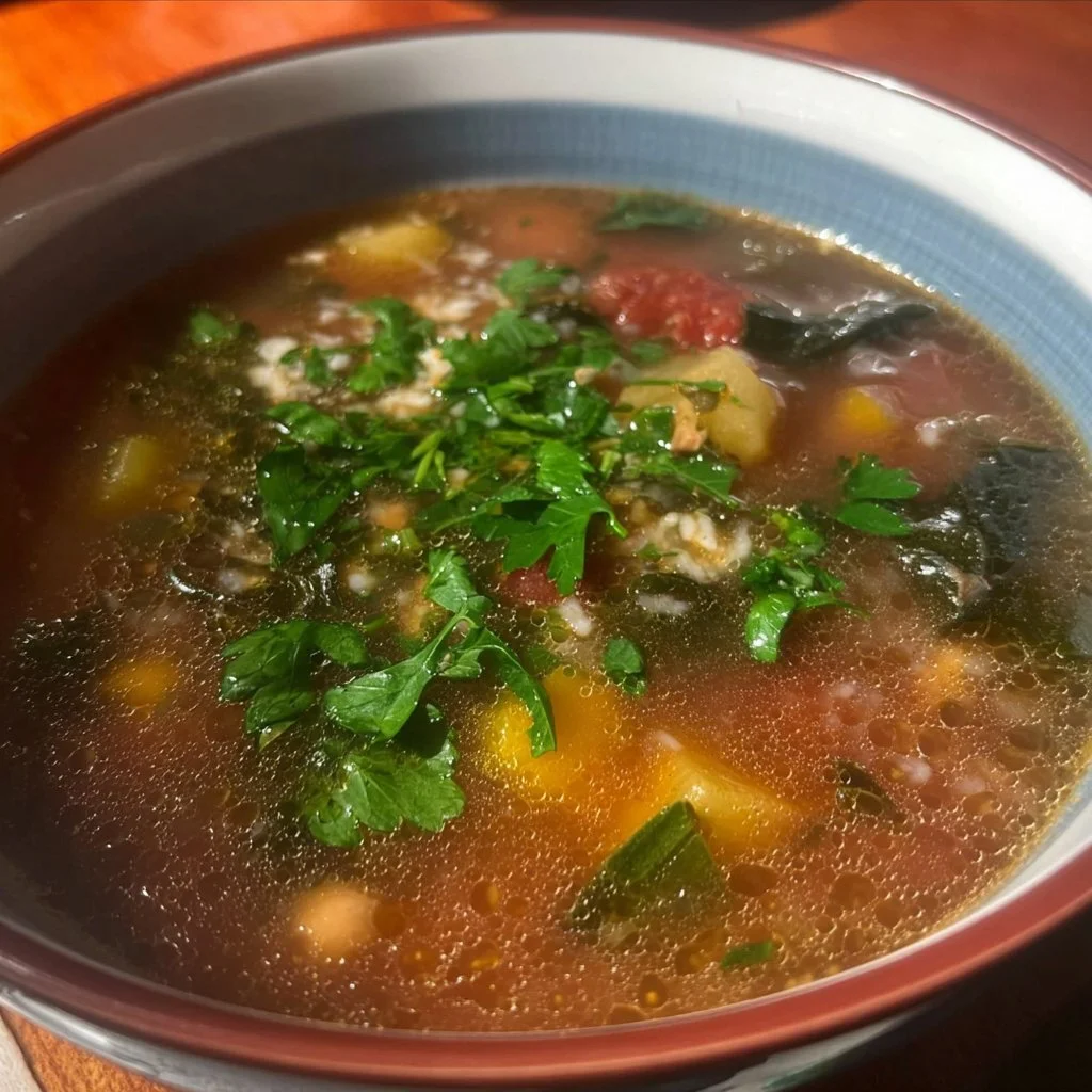 Bowl of healthy harvest soup filled with seasonal vegetables and herbs.