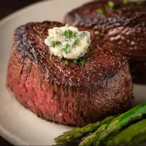 Deliciously cooked Air Fryer Filet Mignon served on a plate with herbs.