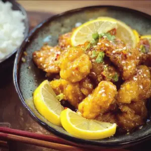 Plate of homemade Chinese lemon chicken with vibrant lemon slices and herbs