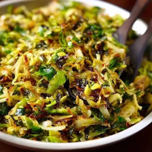 Sautéed shredded Brussels sprouts drizzled with balsamic glaze in a pan