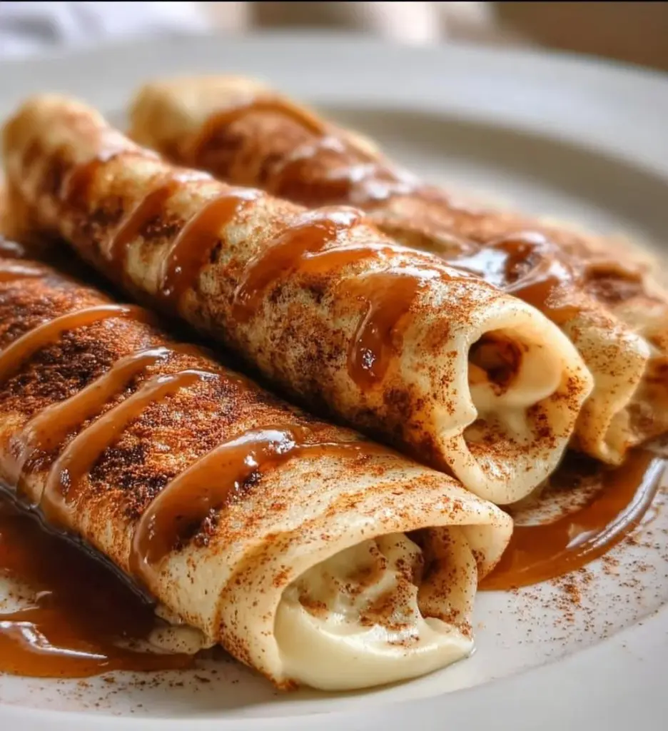 Cinnamon roll protein crepes topped with icing and cinnamon sugar