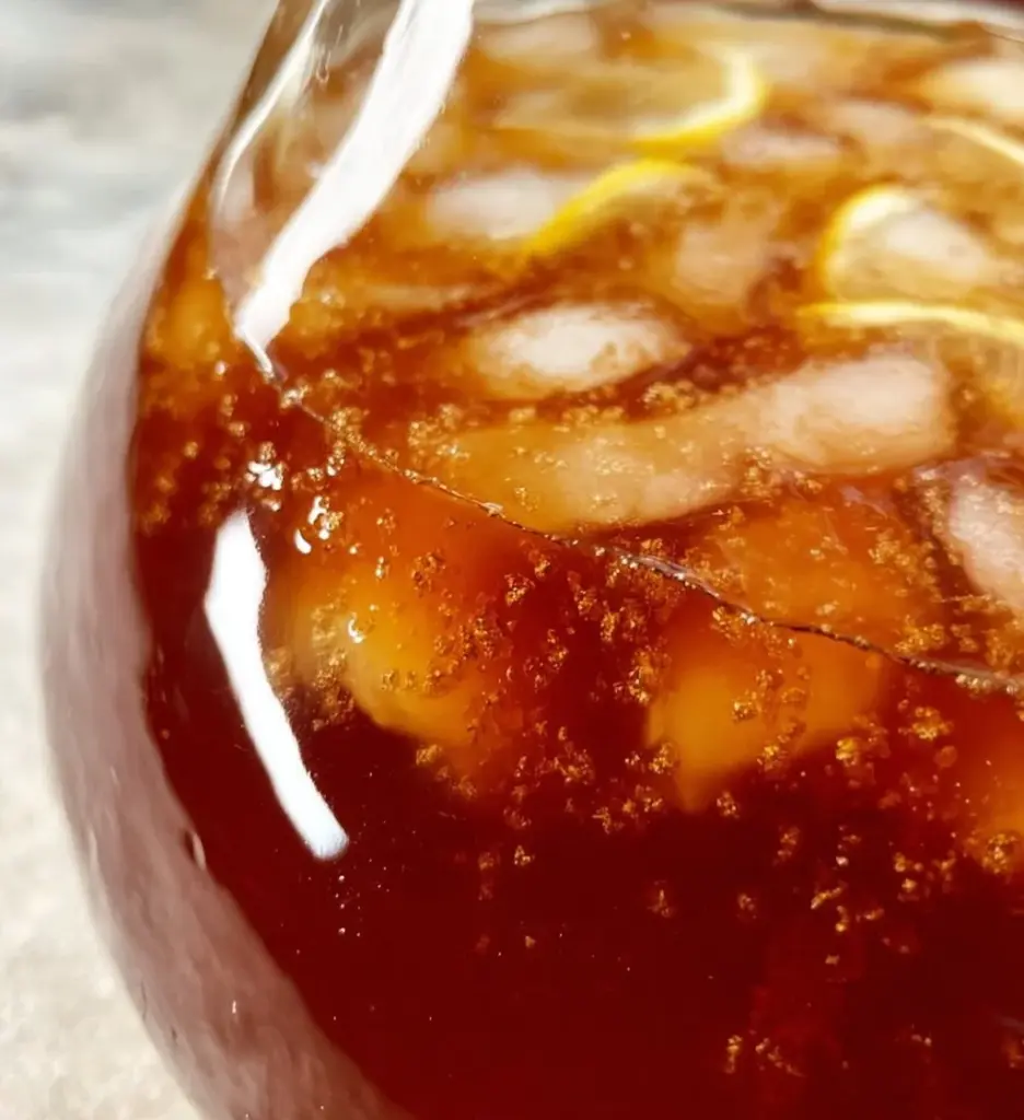 A glass of easy sweet tea with lemon slices and mint leaves.