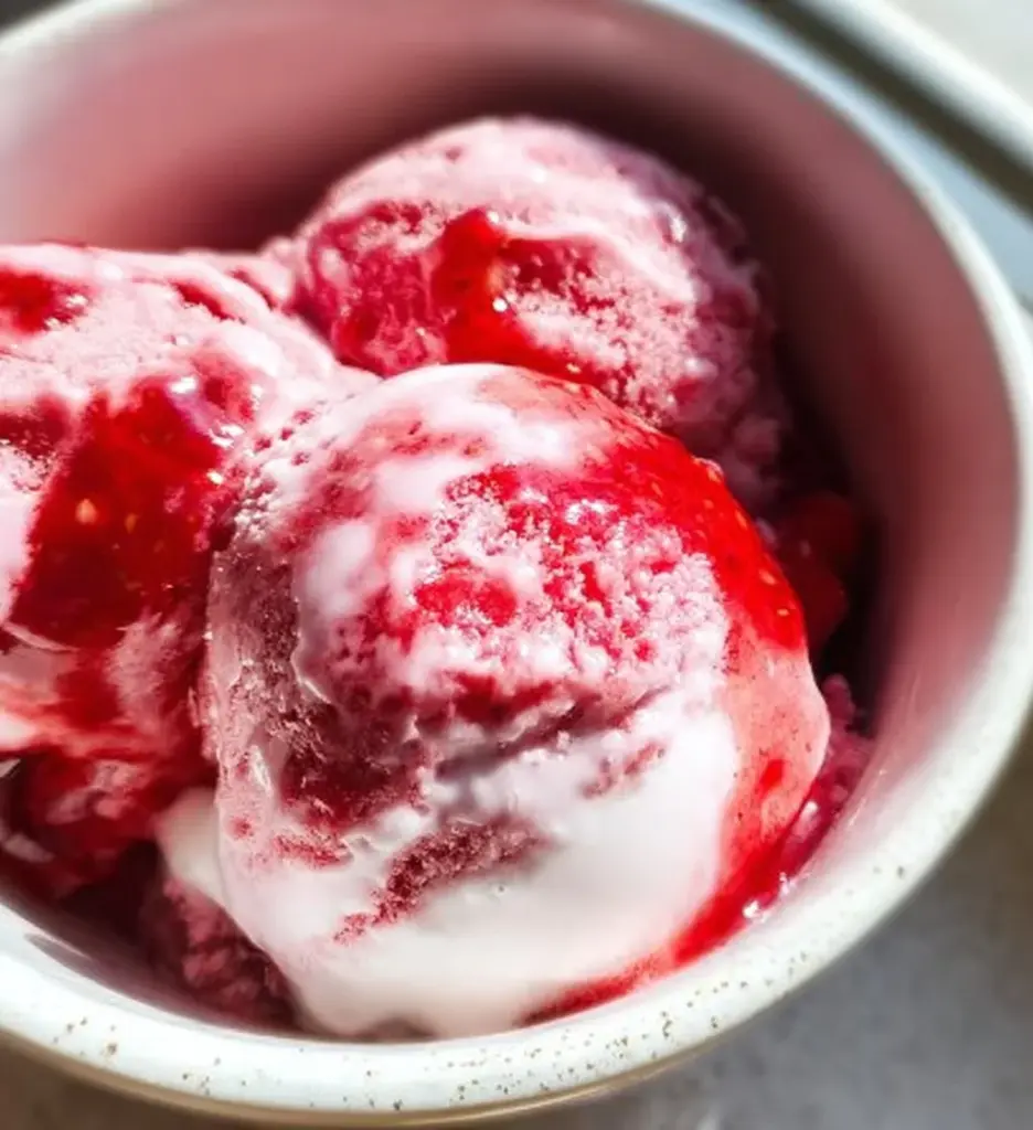 Bowl of strawberry cottage cheese ice cream garnished with fresh strawberries