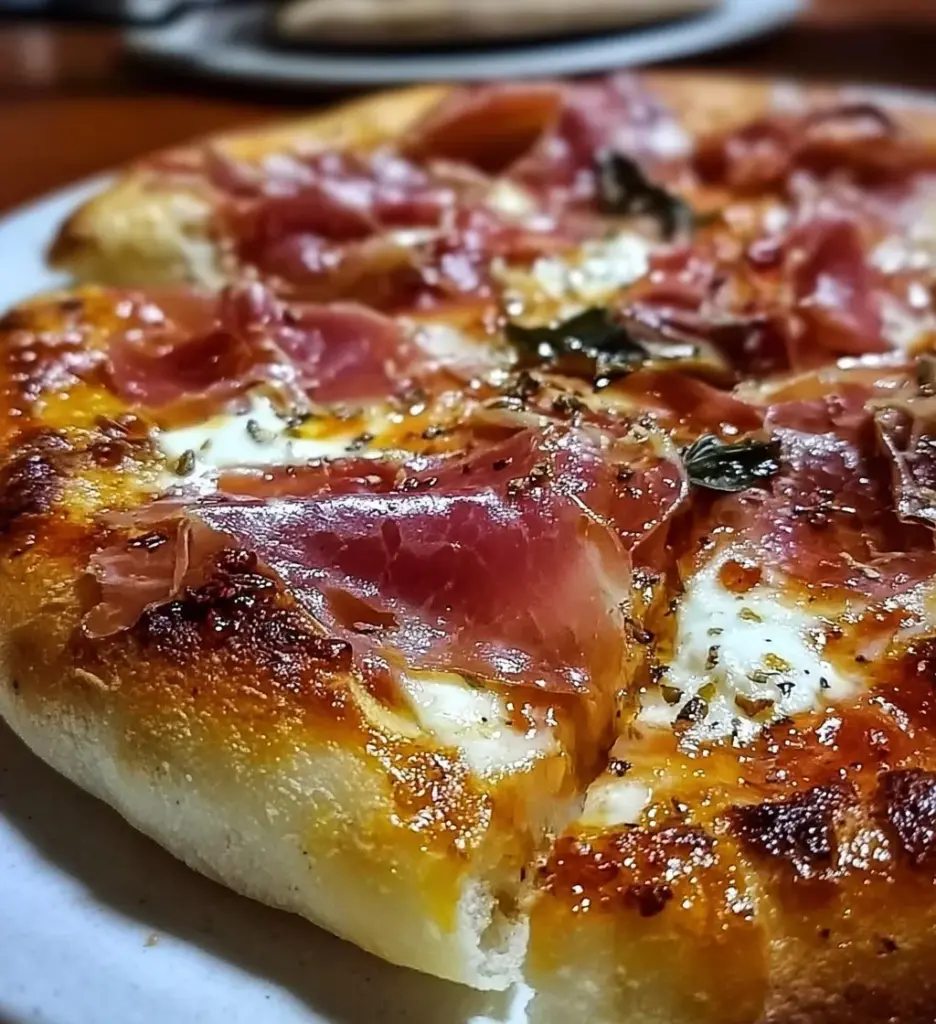 White pizza topped with prosciutto and hot honey on a wooden board.