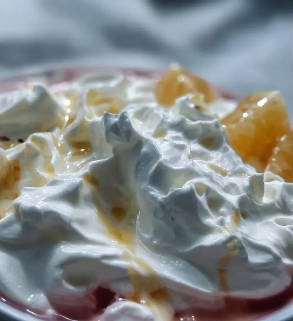 Bowl of yogurt fruit salad topped with fresh berries and banana slices